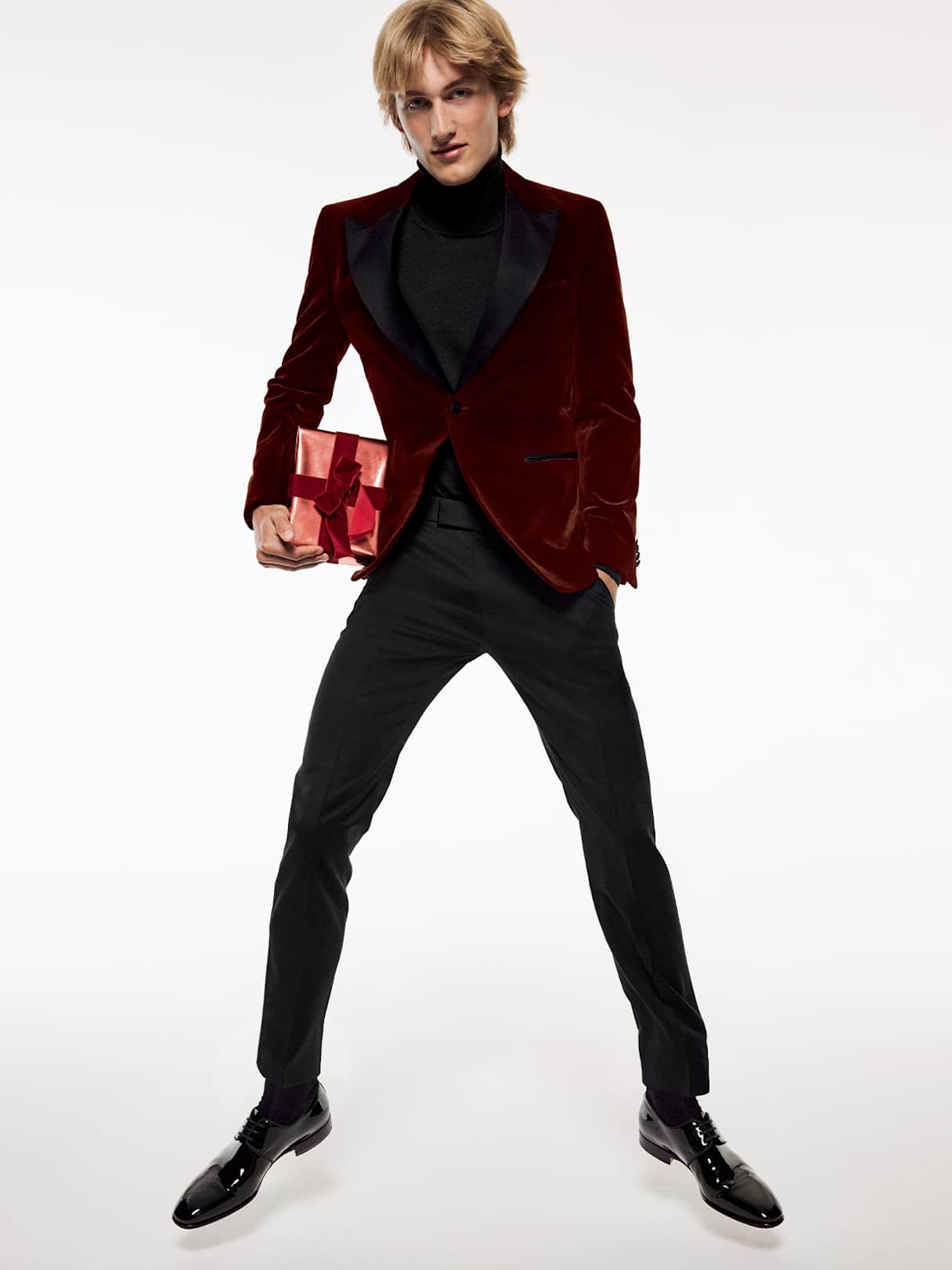Man in a burgundy velvet blazer holding a present